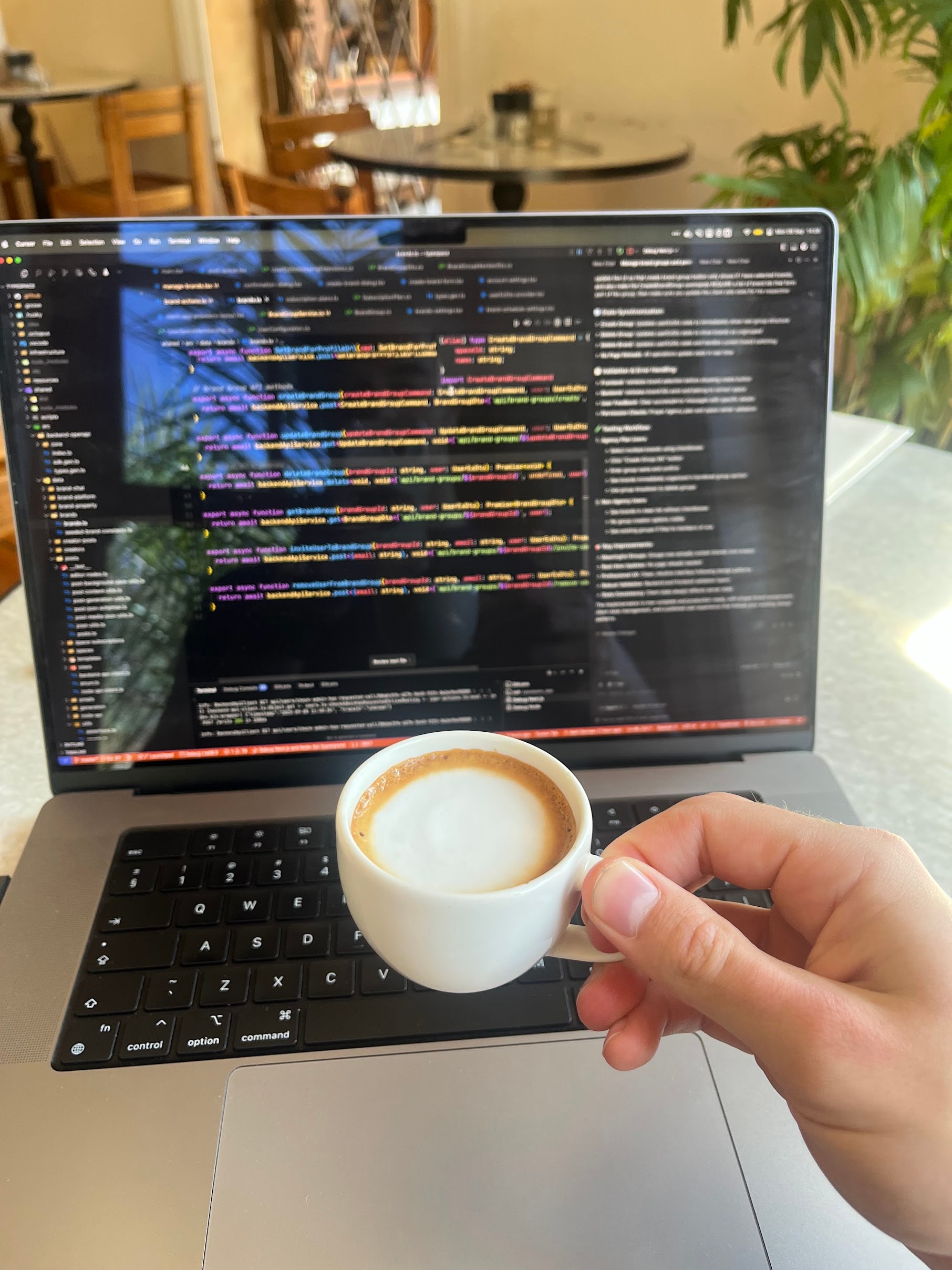 A full coffee cup held beside a laptop displaying code.